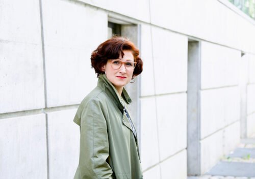 Ferda Ataman vor einer hellen Hausfassade.
