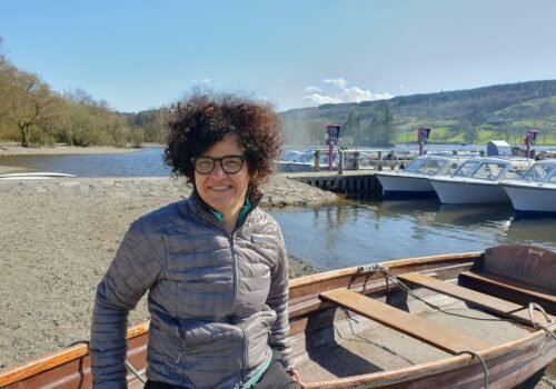 Die Klimaforscherin Sasha Kosanic lehnt an einem Ruderboot an der Küste vom Lake District