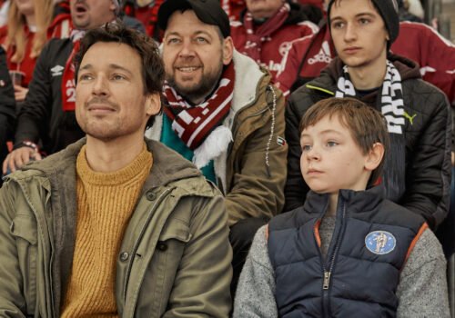Bild einer Szene aus dem Film Wochenendrebellen: Vater und Sohn sitzen im Stadion.