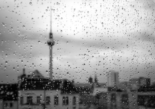 Regnerisches Wetter - Regentropfen laufen eine Fensterscheibe hinunter. Im Hintergrund ist der Berliner Fernsehturm zu sehen.