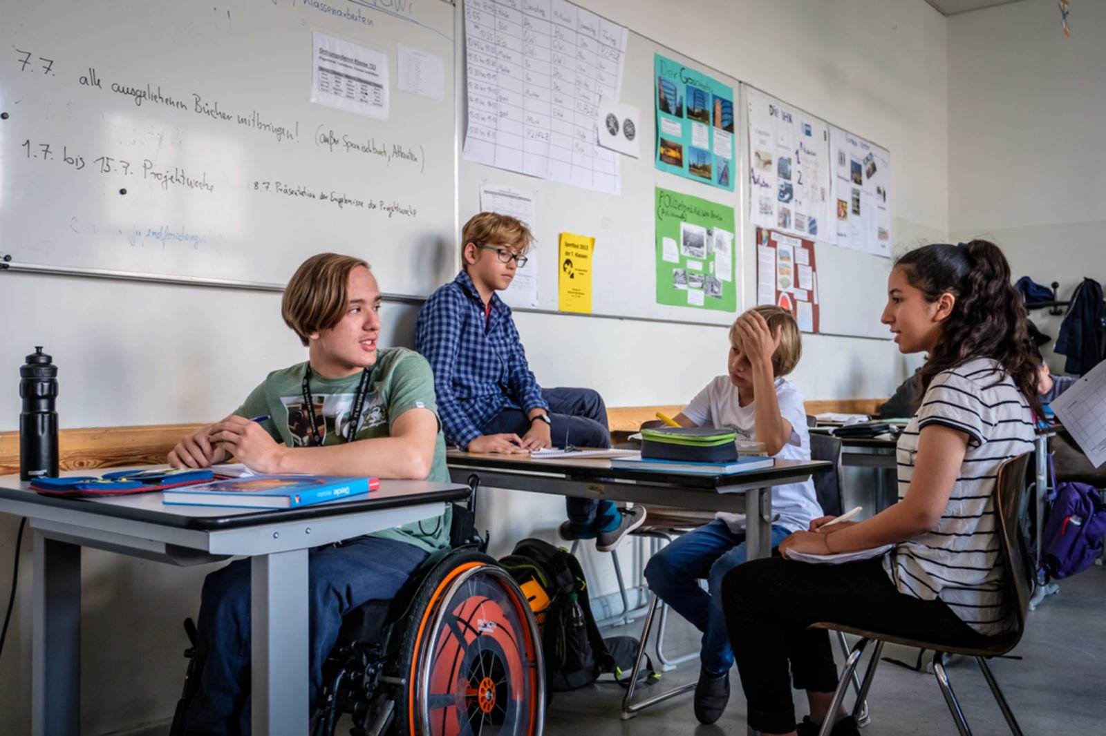 Inklusion an Schulen: Eine Schulklasse, vorne links am Tisch sitzt ein Junge im Rollstuhl.