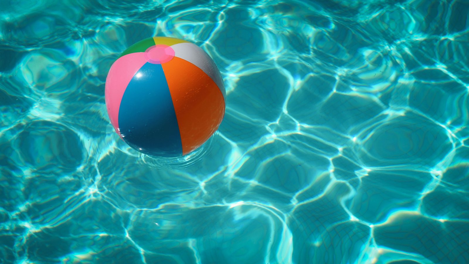 Ein bunter mit Luft gefüllter Plastikball schwimmt auf Wasser.